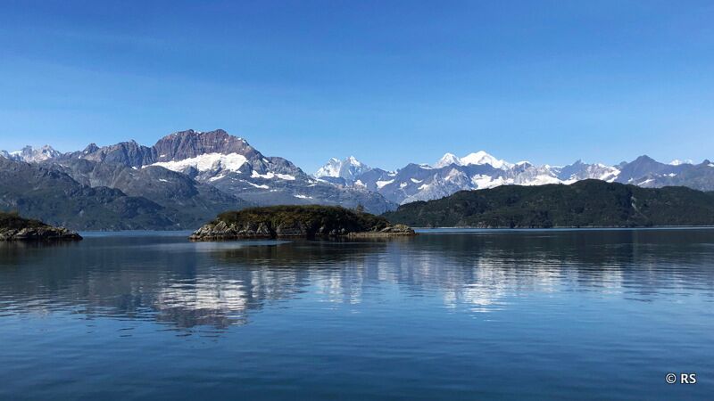 Bewaldete Bergrücken und in der Ferne die Berglandschaften mit Schneefeldern im Glacier Bay Nationalpark in Alaska.
